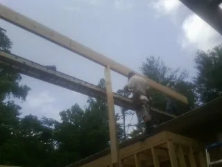 Carpenter setting a ridge beam over a new addition frame — Ice Dam Removal by Roofing Brothers in Saint Petersburg