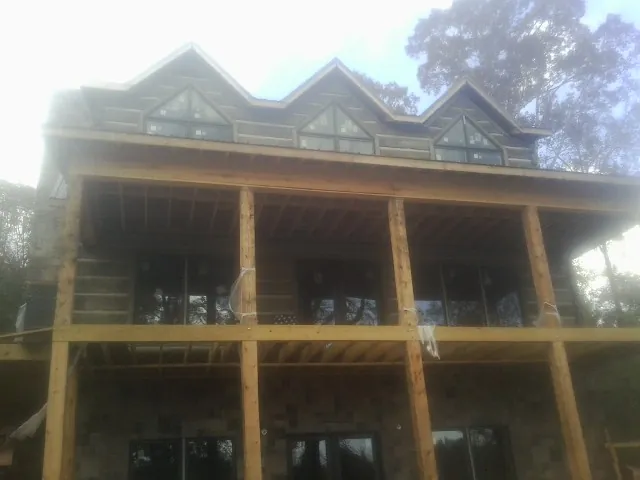 Dormers and porch framing on a large log home under construction — Roof Coating work by our crew in Saint Petersburg