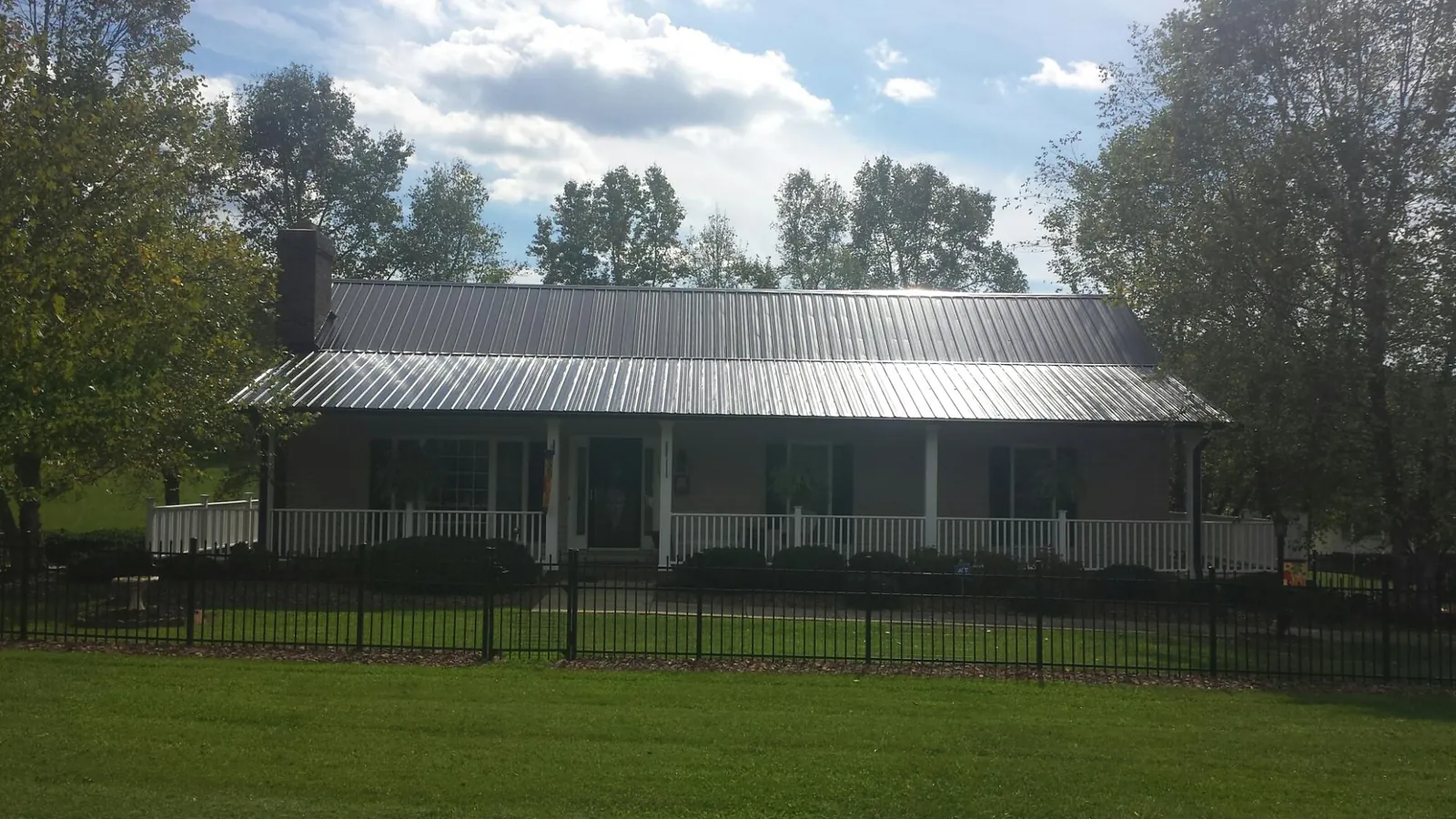 Gray metal roof on a brick ranch with a full width front porch — Gutter Guard Installation work by our crew in Saint Petersburg