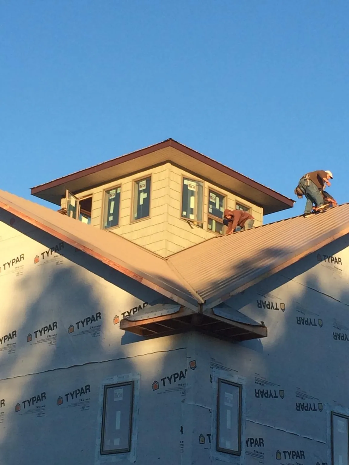 Roofers working around a rooftop cupola on a new metal roof at sunset — Roof Waterproofing in Saint Petersburg by Roofing Brothers